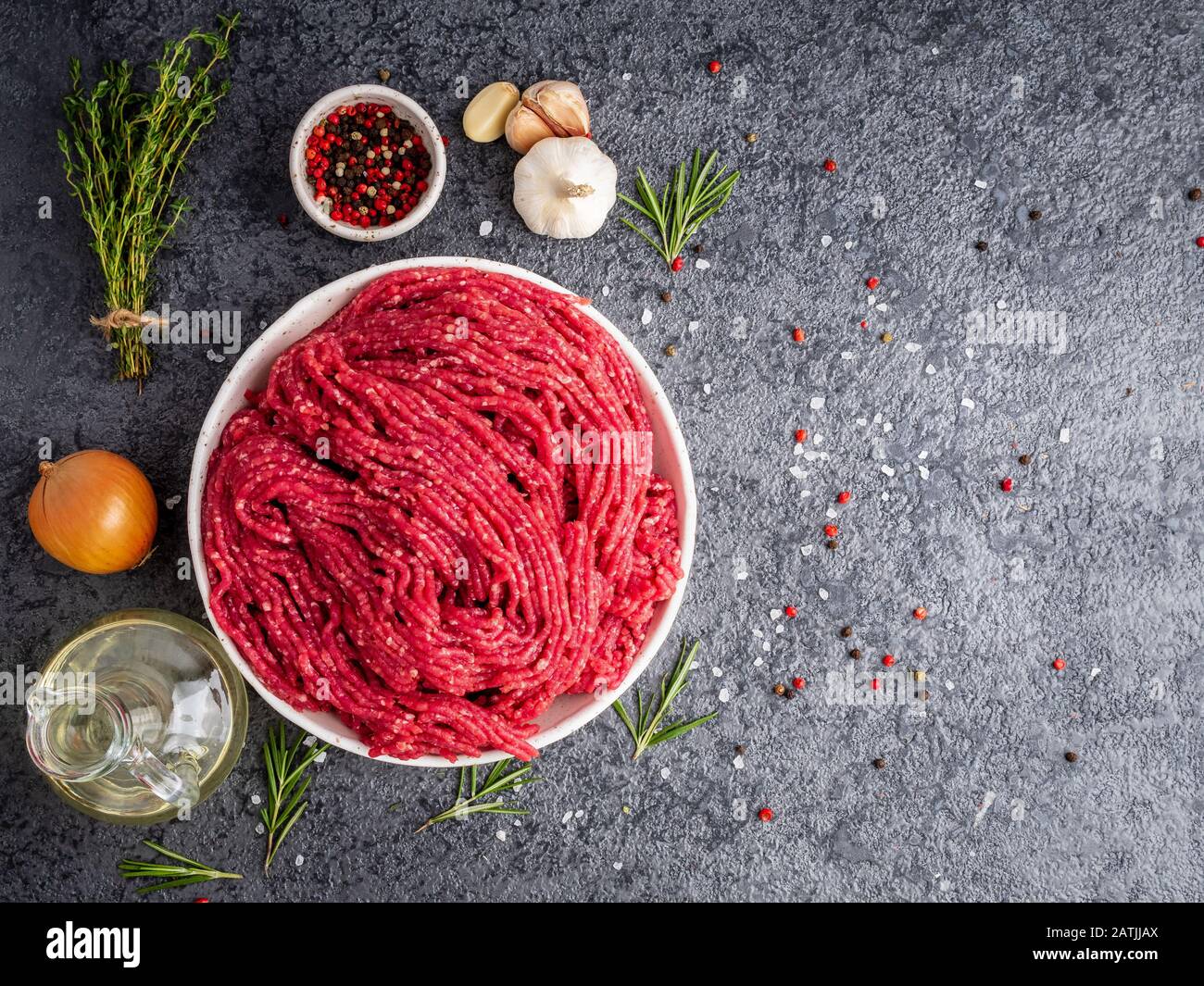 Mince beef, ground meat with ingredients for cooking on dark gray