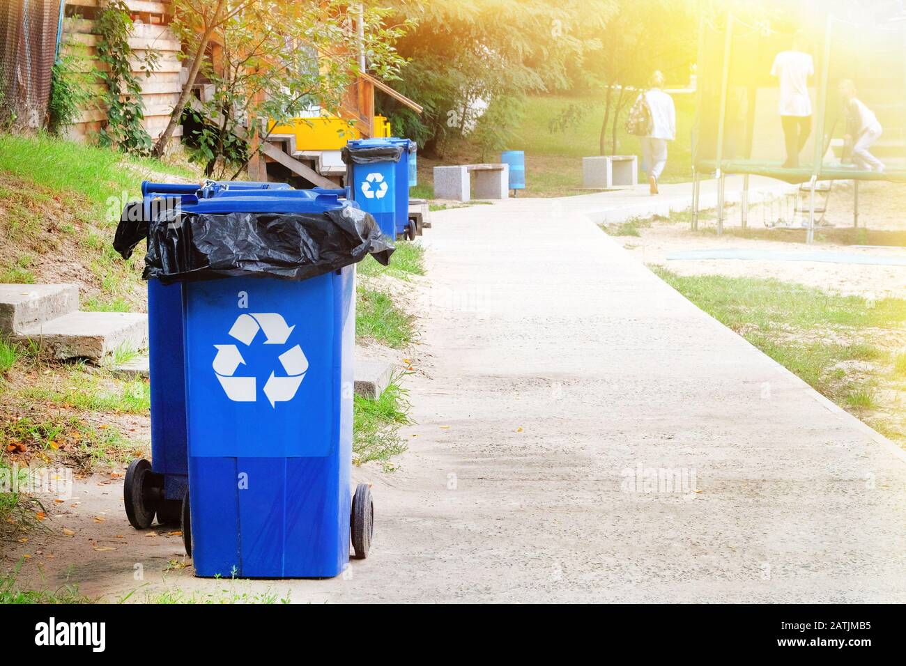 Waste recycling concept. Garbage collection. Blue containers for further processing of trash. Ecology and recycle garbage concept.  Sunlight rays. Stock Photo
