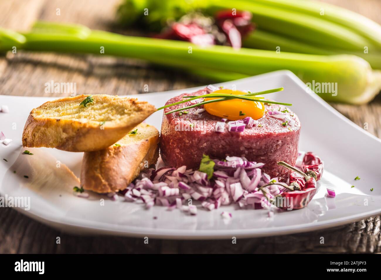 Beef tartare with egg yolk red onion chili peppers herbs and bruschetta Stock Photo