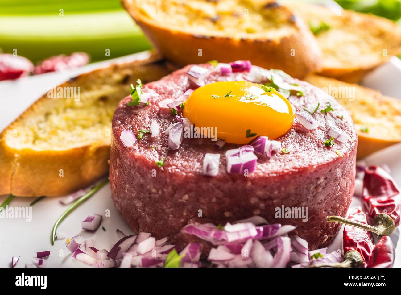 Beef tartare with egg yolk red onion chili peppers herbs and bruschetta Stock Photo