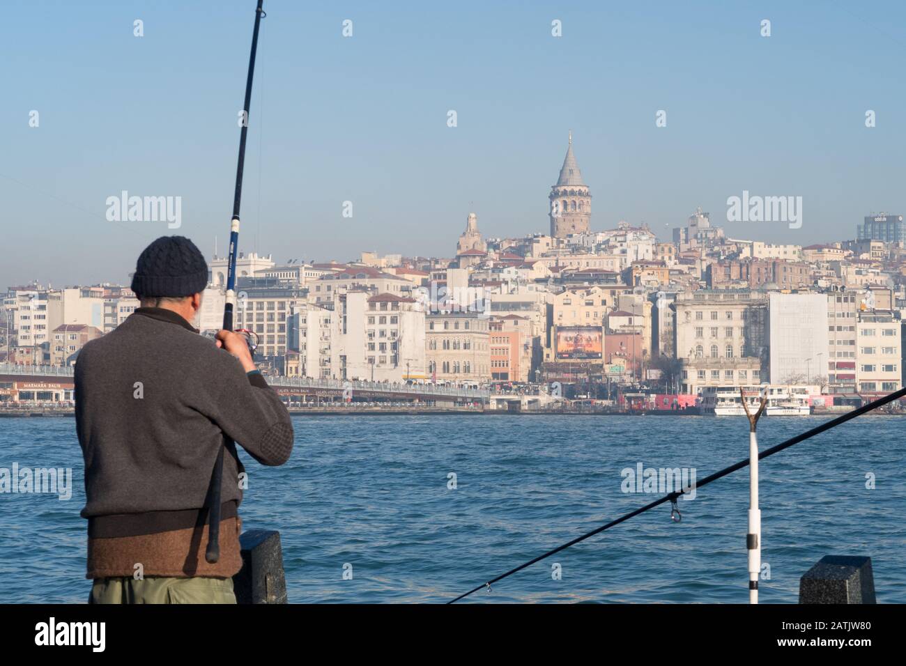 Istanbul, Turkey - Jan 10, 2020: Fishermen on the Golden Horn, in Eminonu district near Galata Bridge, in background Beyoglu district, Istanbul. Turke Stock Photo