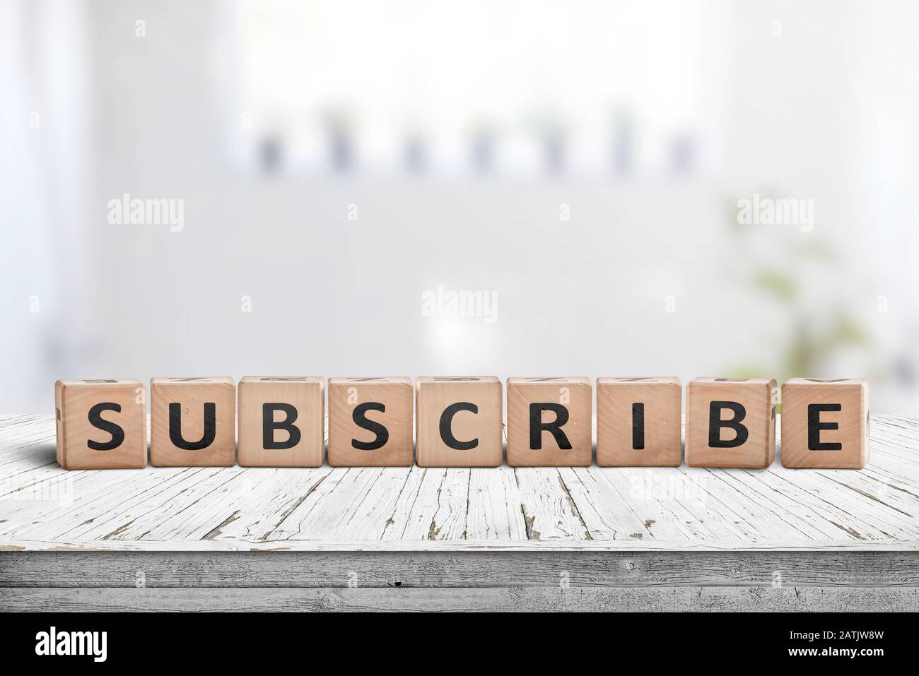 Subscribe word on a wooden sign on a table in a bright room Stock Photo