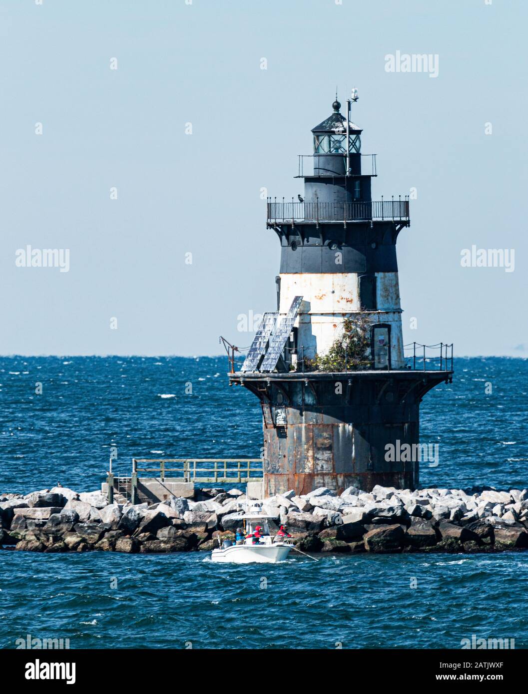 People are in a small boat fishing in front of the Orient Point