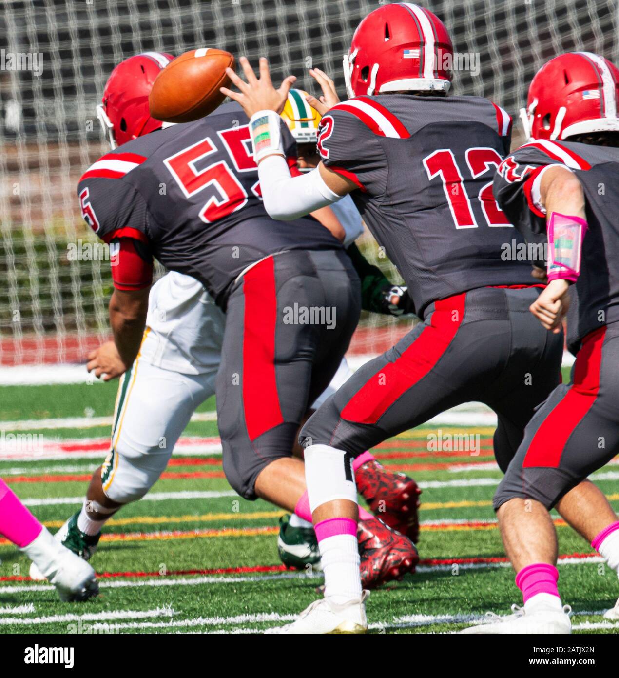 High school quarterback is receiving the ball from the shot gun to start the play during a game. Stock Photo