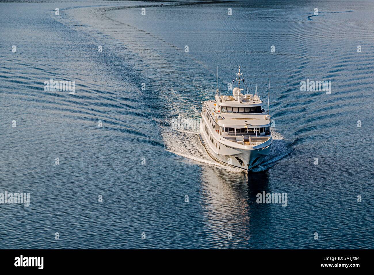 The Australian mega yacht True North is underway in the waters of Papua New Guinea, its wake spreading in wide arcs behind the ship. Stock Photo