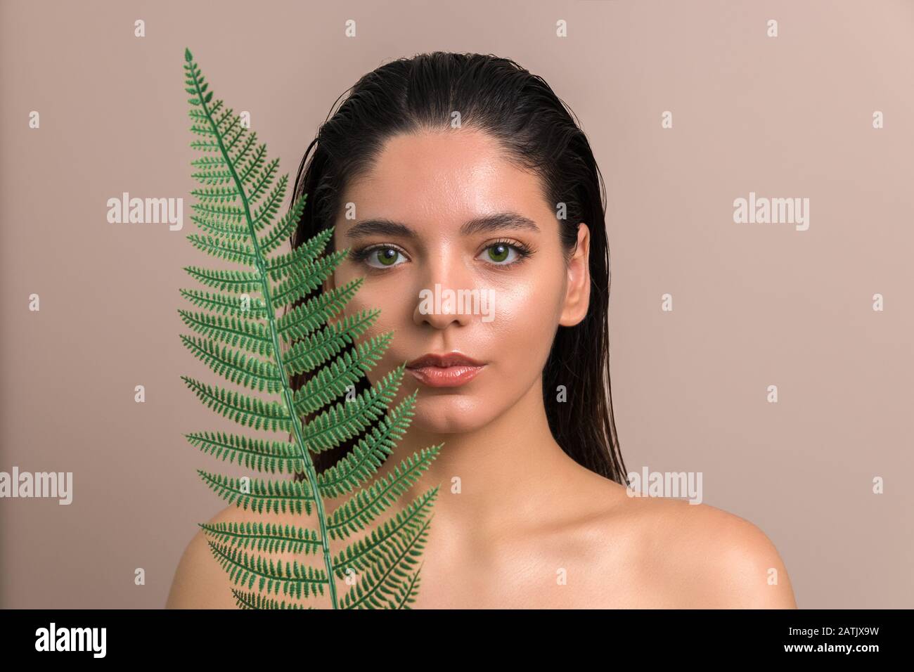 portrait of attractive woman with shiny skin face looking out of palm