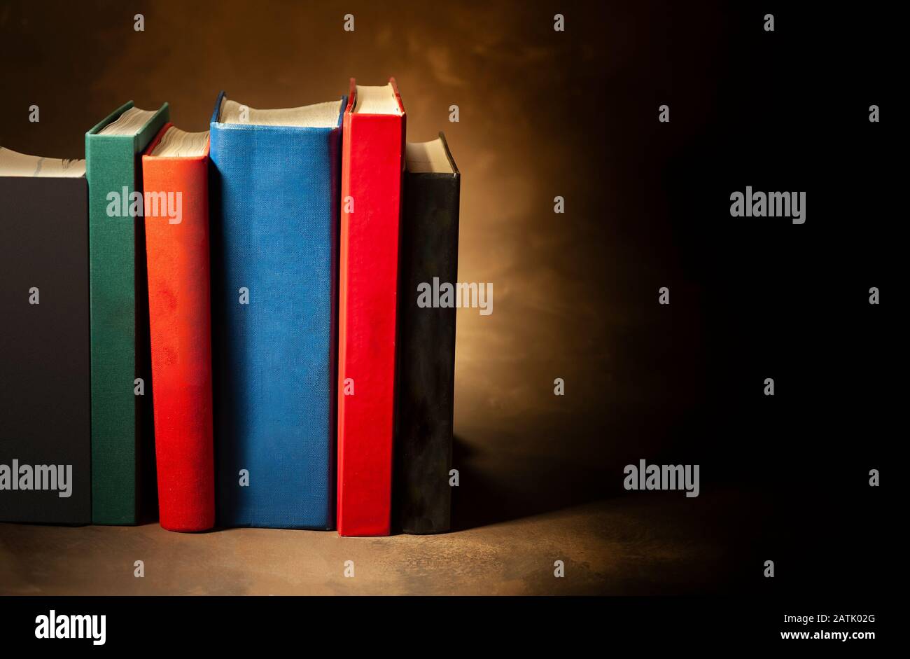 Stack of hardcover books on brown background, space for text on the right Stock Photo