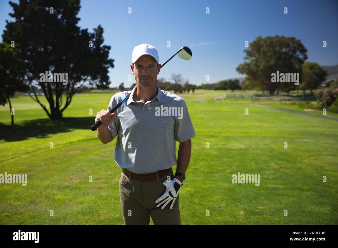 Golfer looking at camera and holding golf club Stock Photo - Alamy