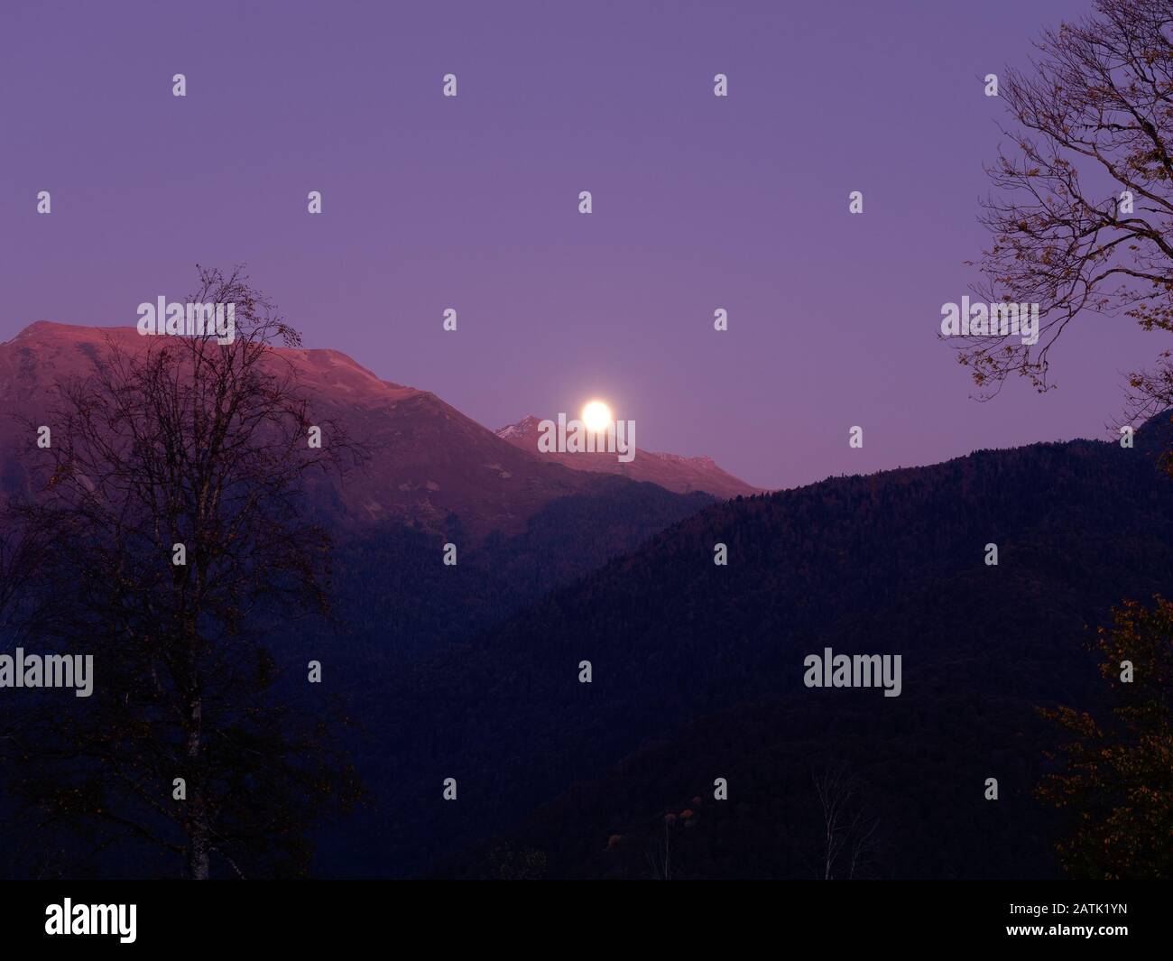The moon rises over mountain valley in the blue sky Stock Photo - Alamy