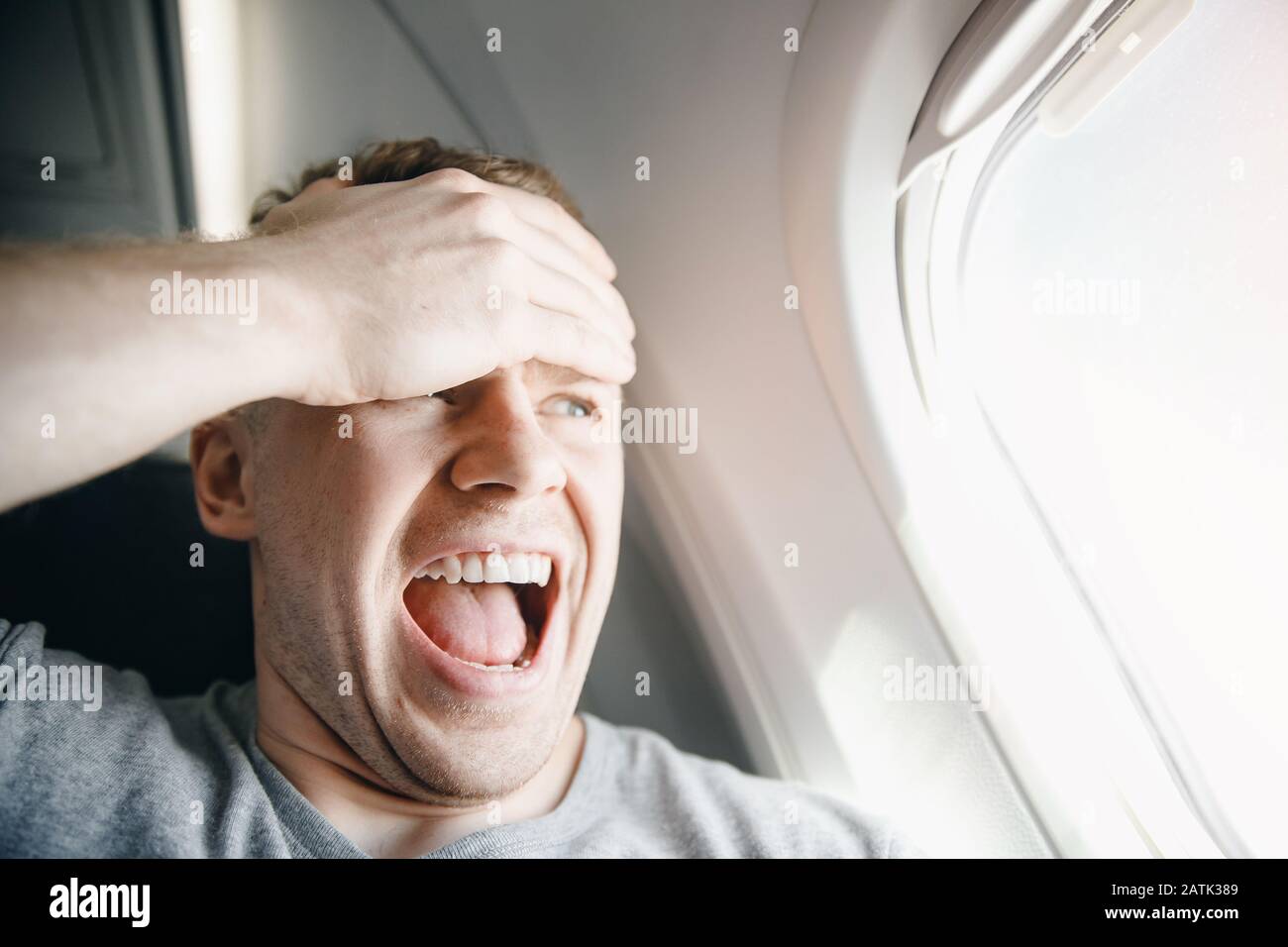 Passenger man in plane clutches his head, afraid of heights and flight. Scream and cry expression Stock Photo