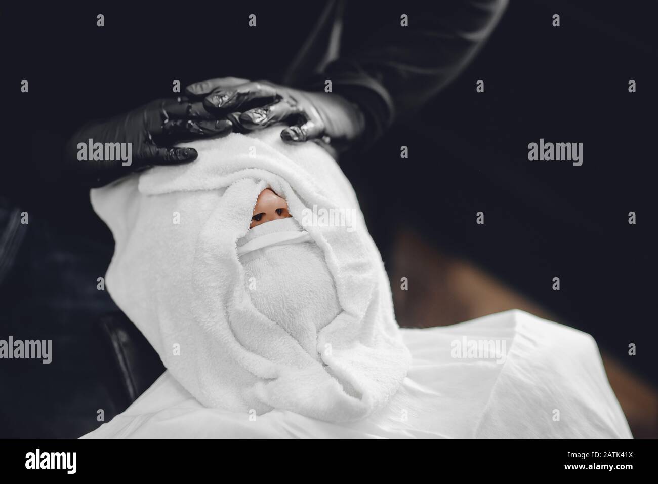 Barber steam face skin of man with hot towel before royal shave in