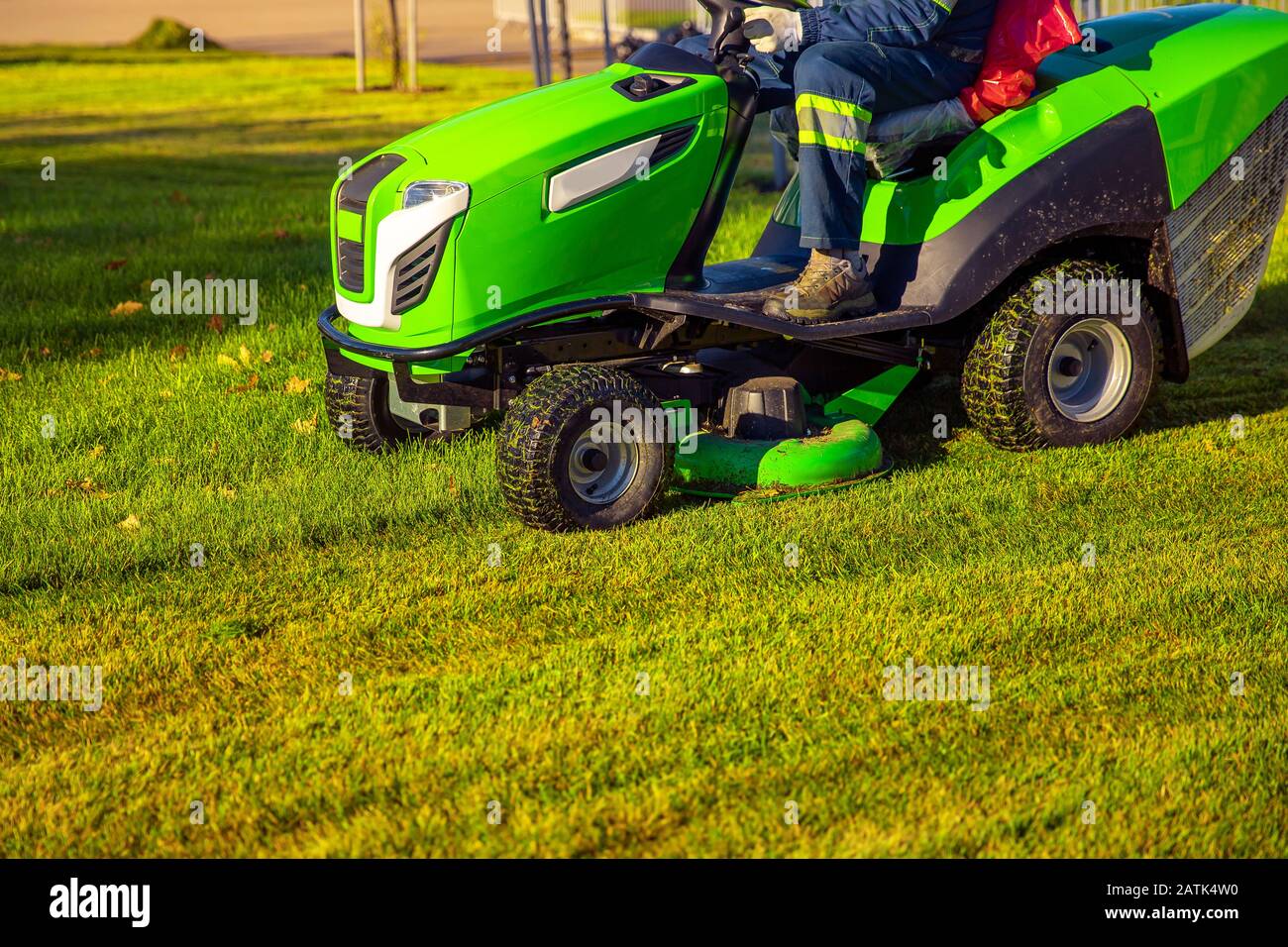 Gardener worker on lawn mower tractor cuts green grass Stock Photo Alamy