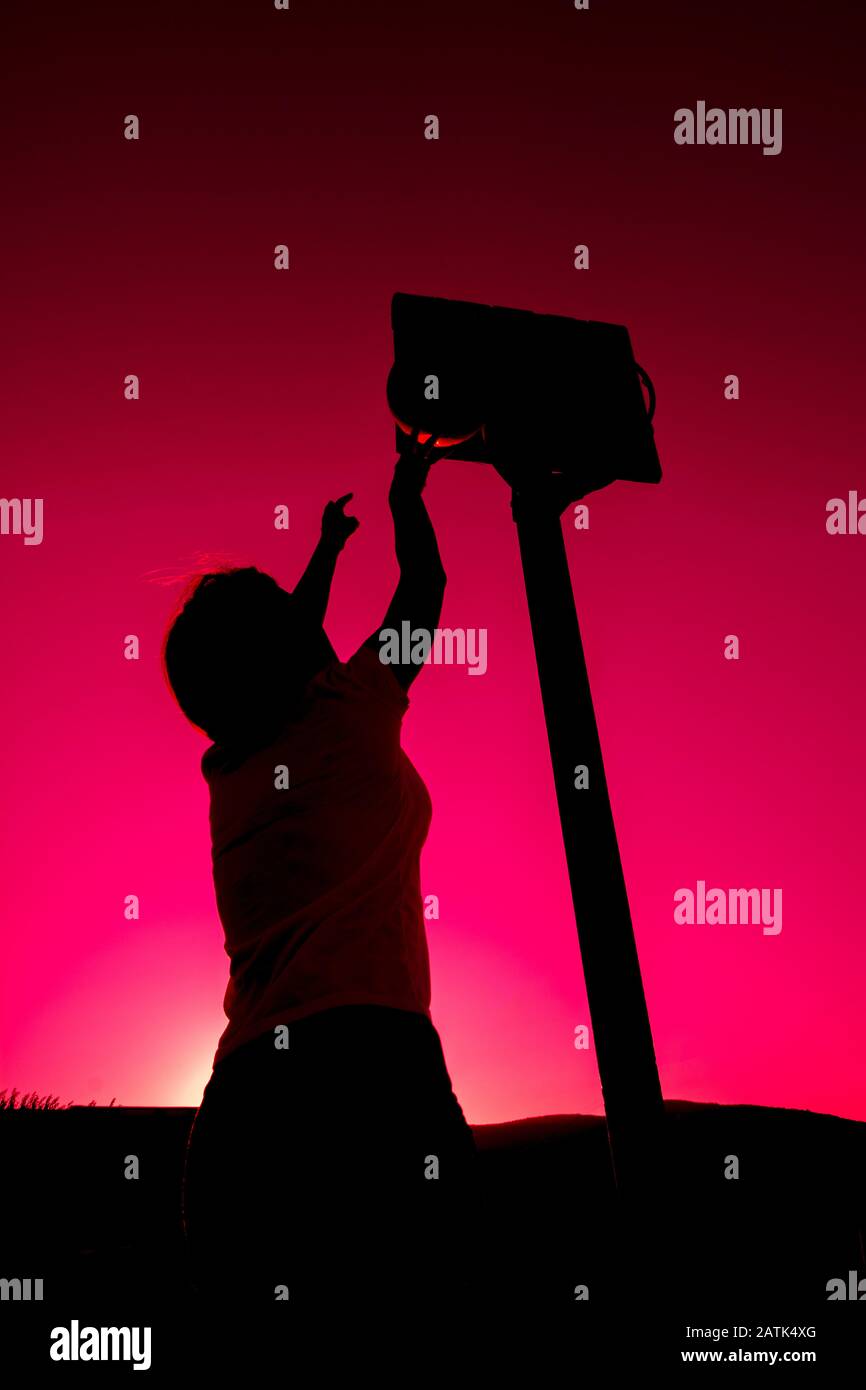 Silhouette of woman playing basketball Stock Photo