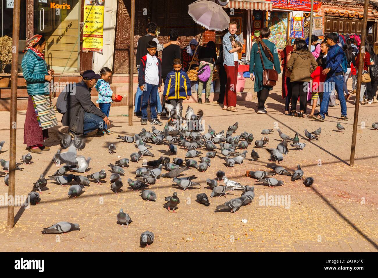 Katamandu, Nepal - November 12, 2016: Nepalese children feed pigeons in Boudhanath square in Kathmandu. Bouddha Stupa. Stock Photo