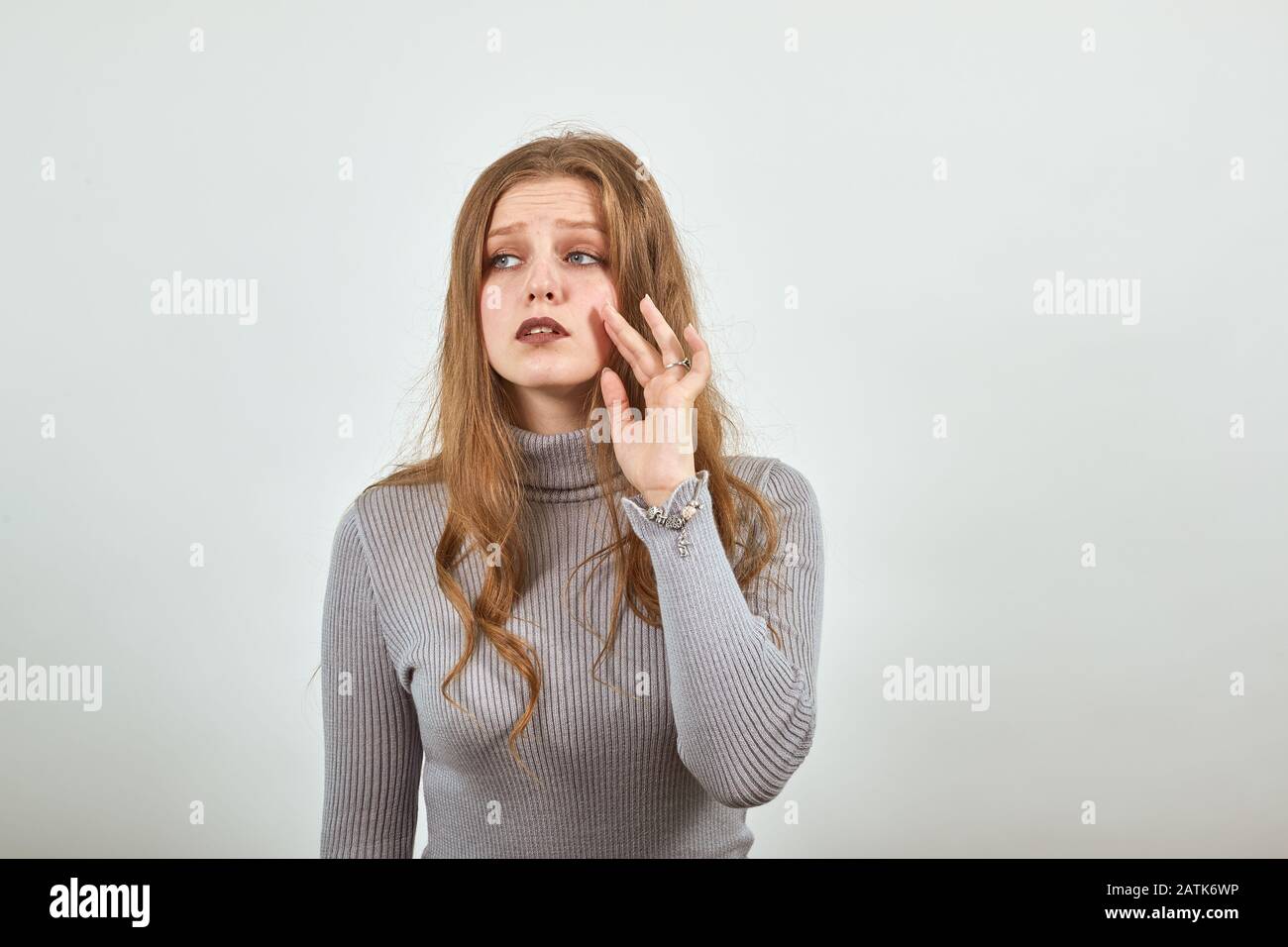 woman in gray sweater with sad look says goodbye waving her hand sadness in eyes Stock Photo