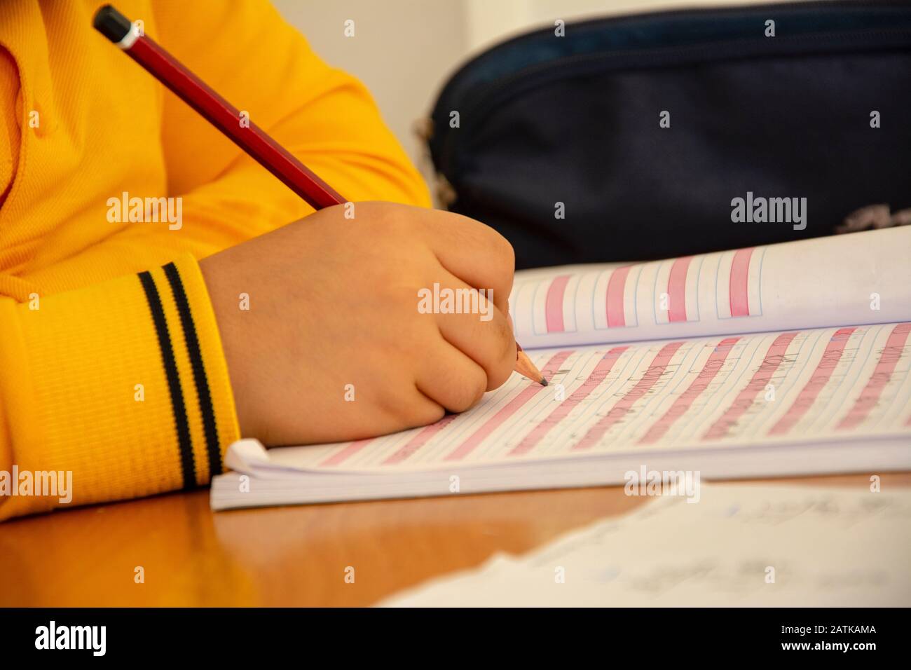 Unrecognizable elementary school student in school uniform is writing in close-up Stock Photo