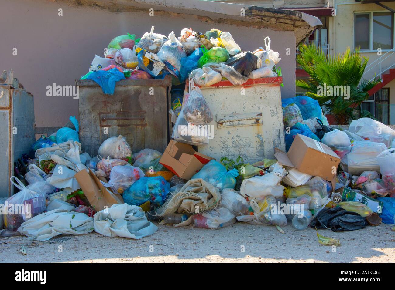 A large, metal, green garbage container and municipal waste, standing on a  dirt road near the fence and trees Stock Photo - Alamy