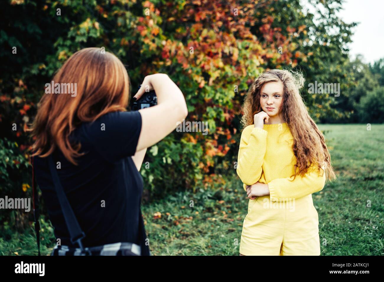 Woman photographer photographing a teenager girl with long red curly hair Stock Photo