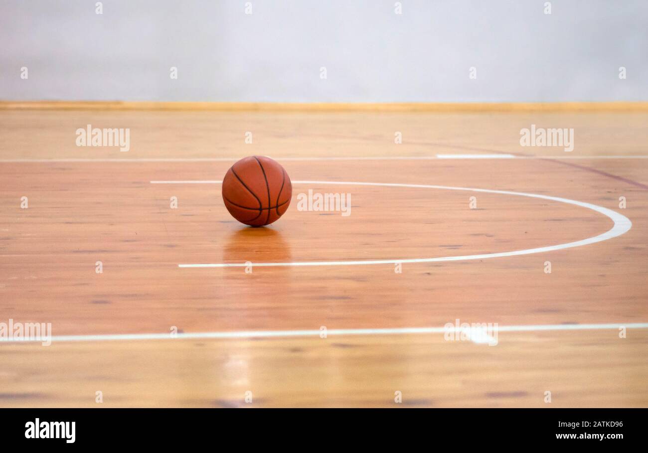 Basketball on Court Floor close up with blurred arena in background Stock Photo