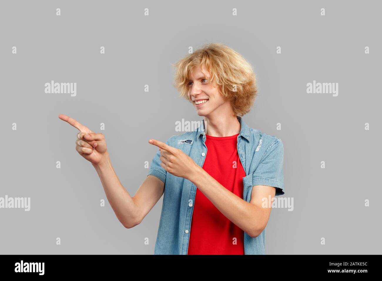 Young man smiling wide, pointing with fingers aside Stock Photo