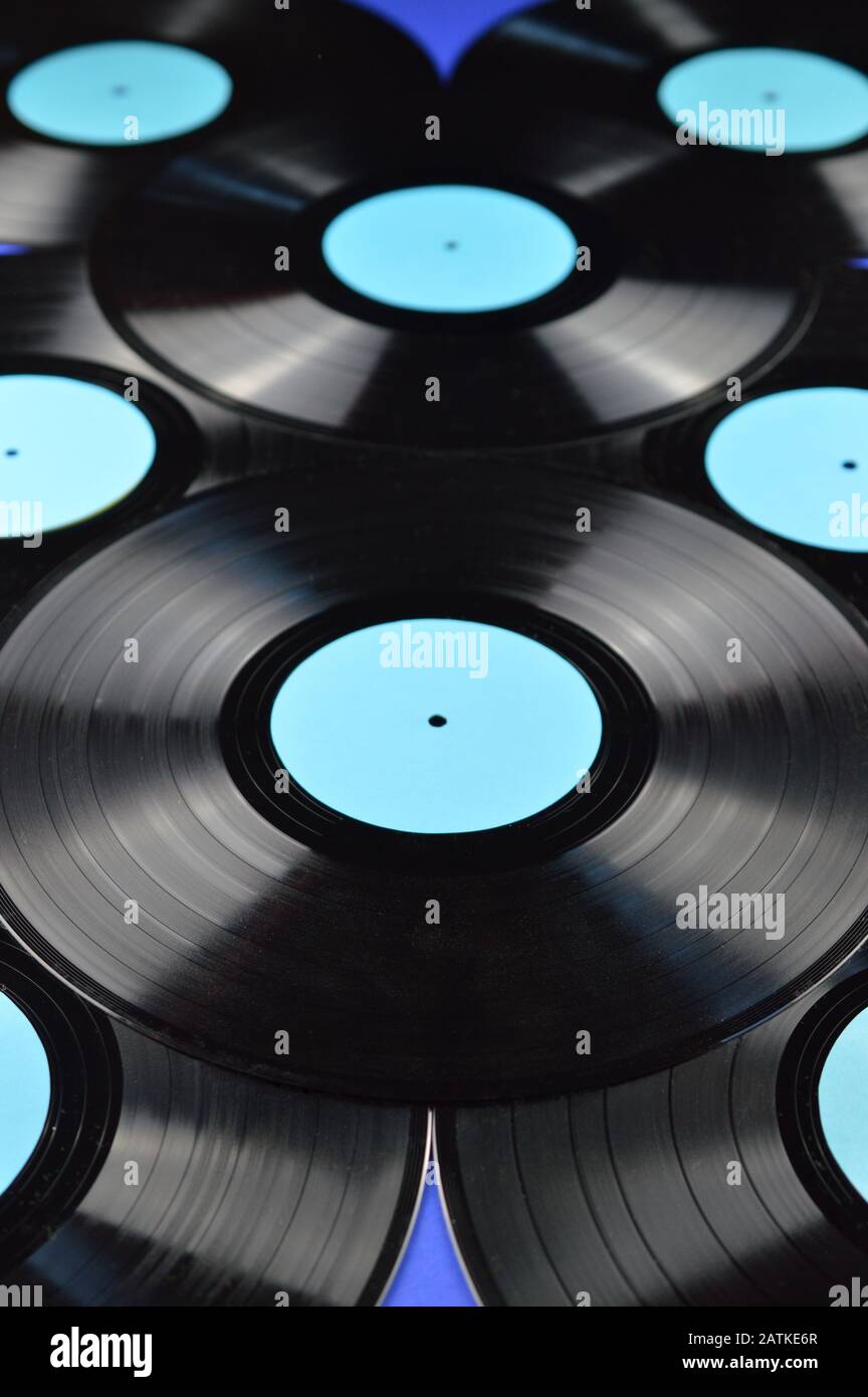 pile of old black vinyl records with blank cyan labels on blue background Stock Photo