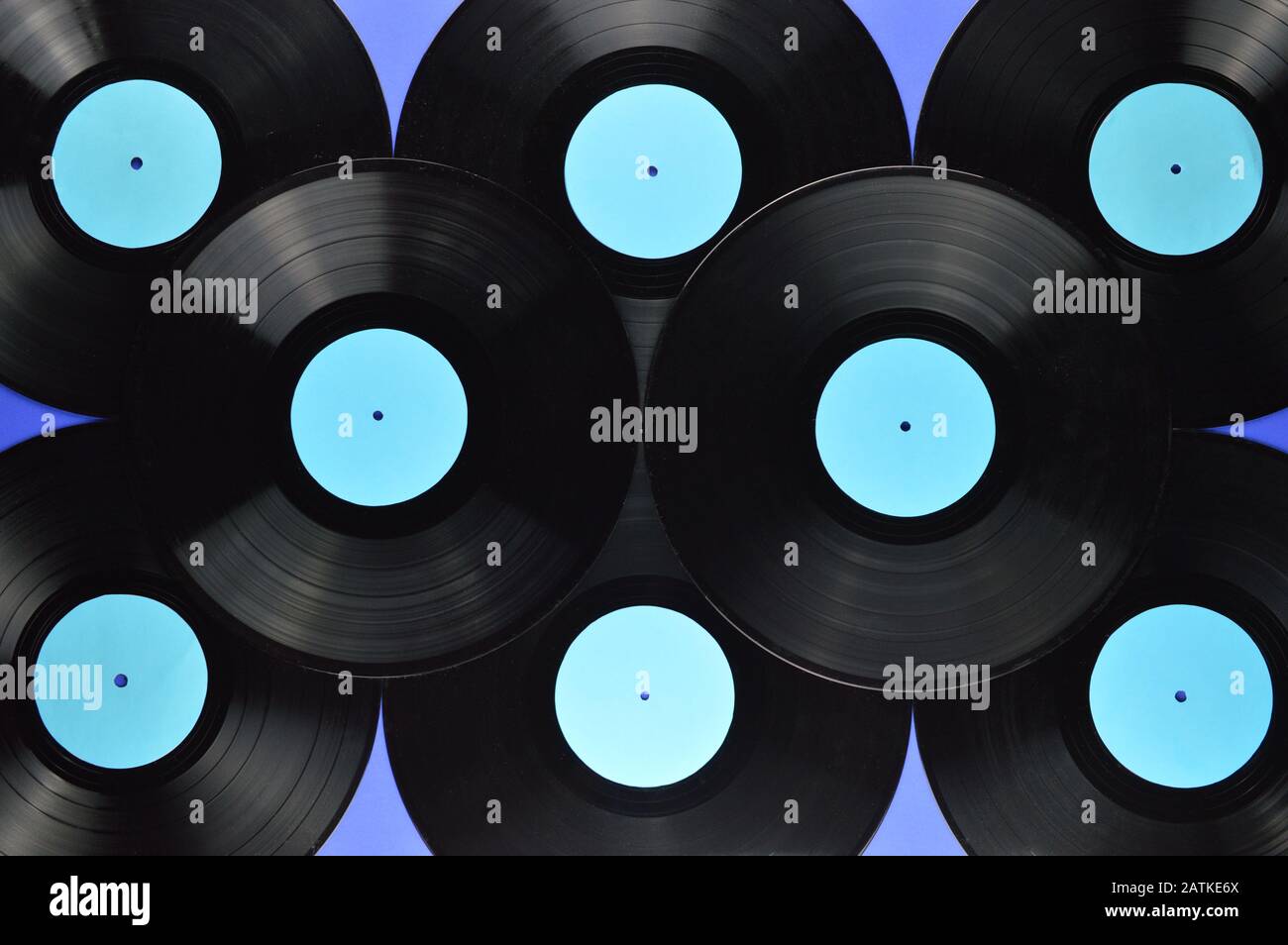 pile of old black vinyl records with blank cyan labels on blue background Stock Photo