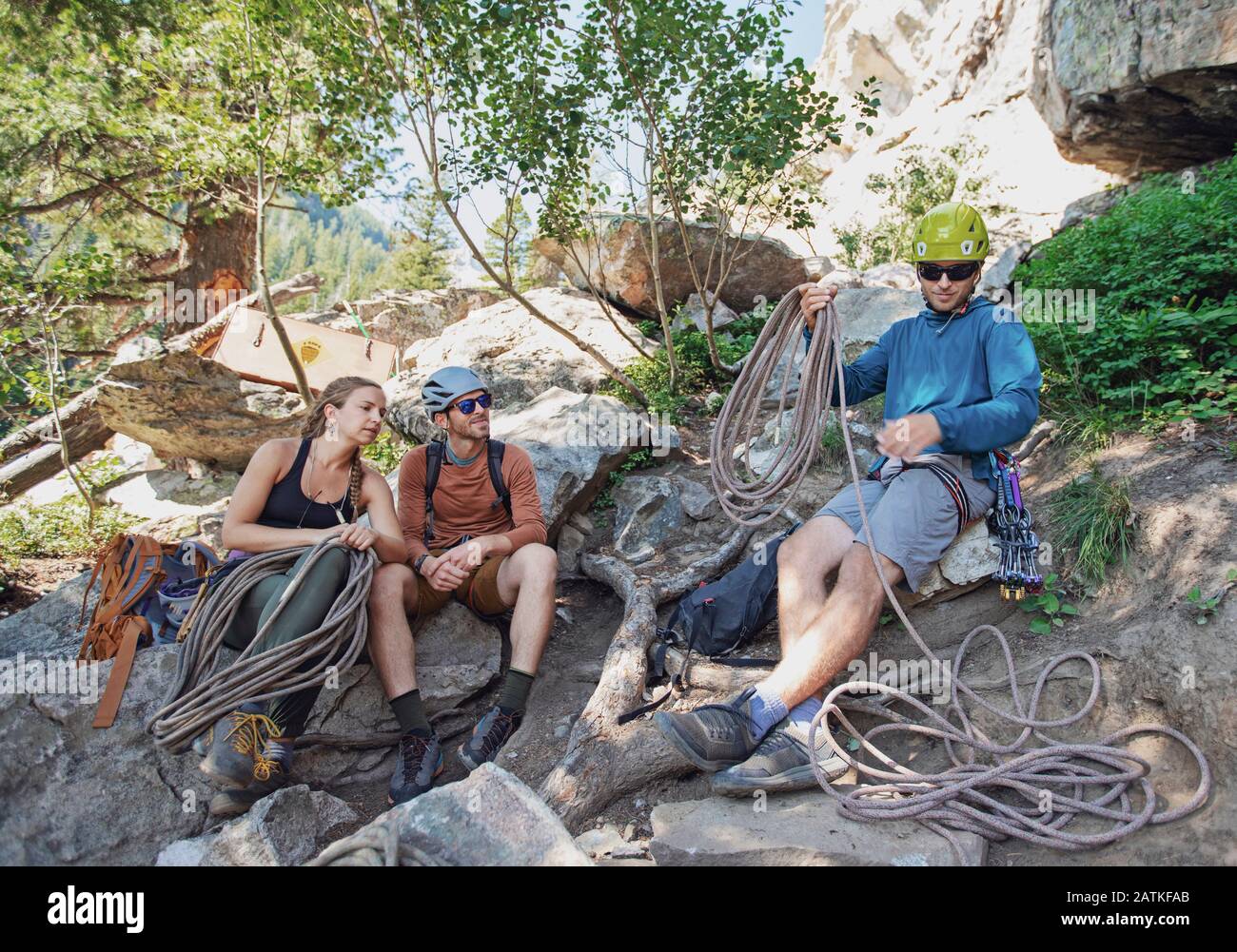 three people prepare rock climbing gear below cliff in Wyoming Stock Photo