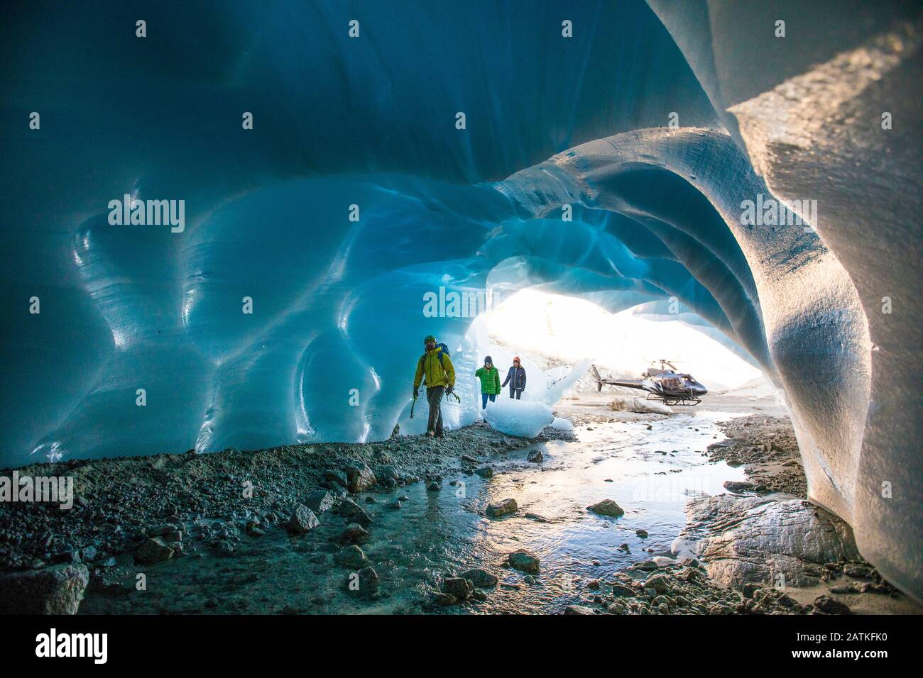 Three ice climbers enter a glacial cave. Stock Photo