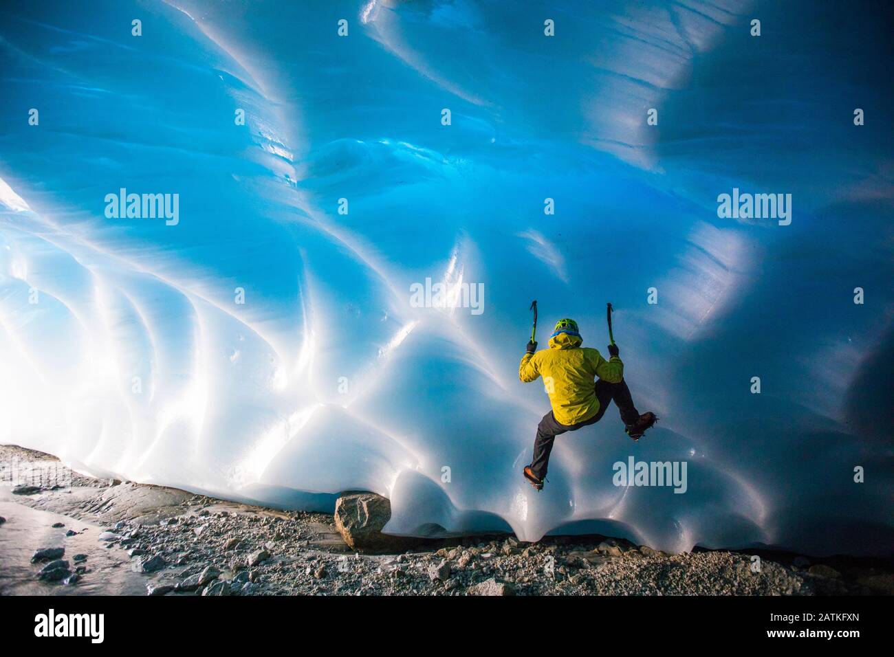 Mountaineer ice climbing on glacial ice in ice cave. Stock Photo