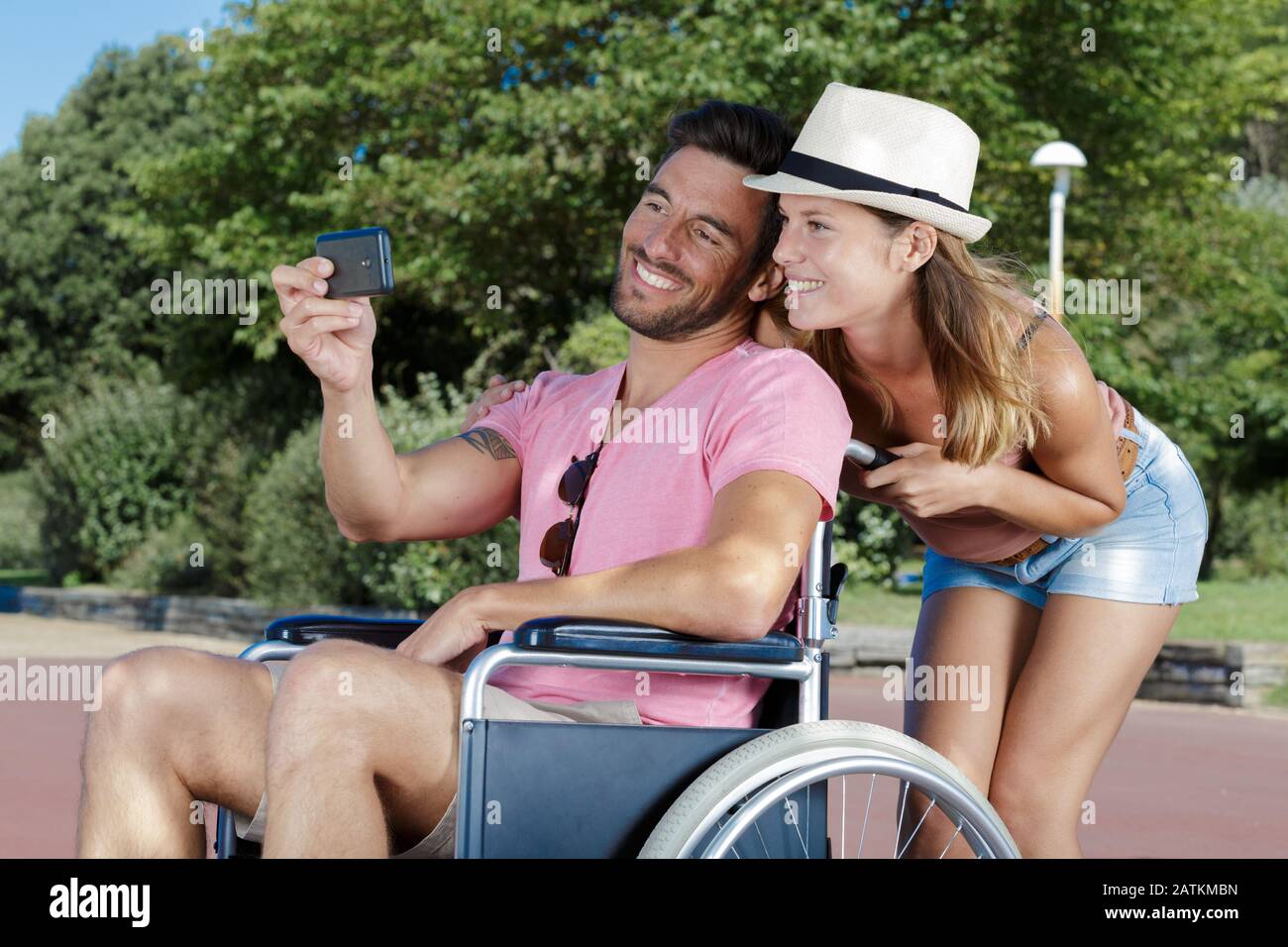young woman in wheelchair and her husband taking selfie outdoors Stock ...