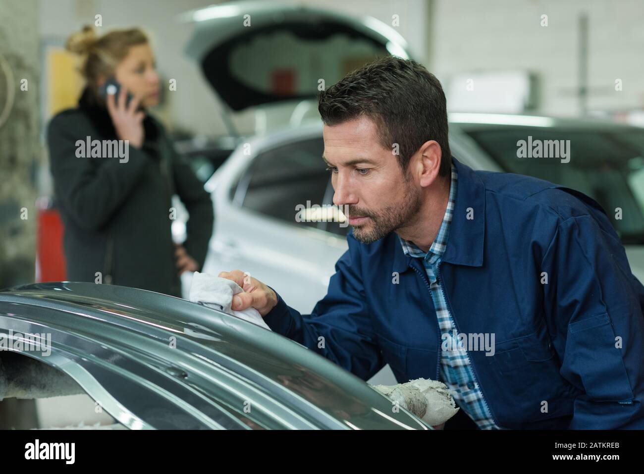 mechanic inspecting a scratch on a car part Stock Photo
