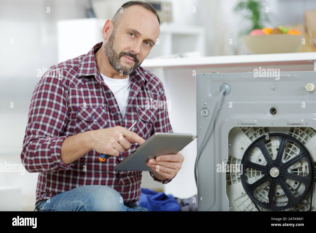 man using tablet pc to fix washing machine Stock Photo