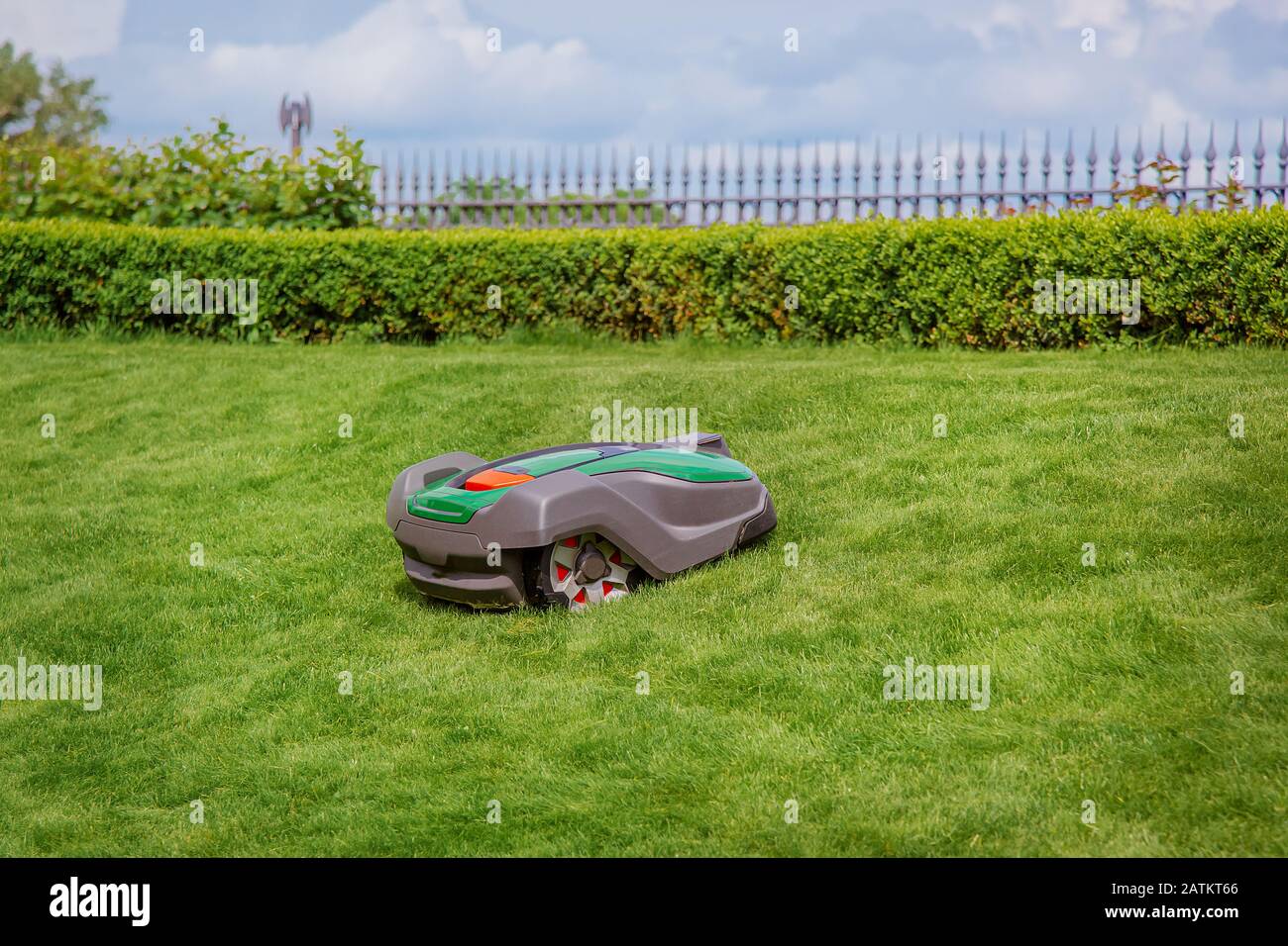 Robotic lawn mower on grass, side view. Garden modern remote technology. Stock Photo