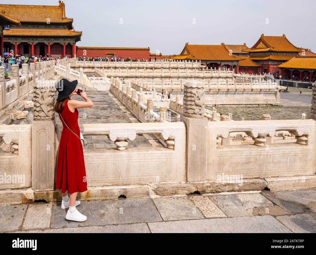 Young Asian woman in a red dress taking a photo on a mobile phone, Hall of Preserved Harmony (Baohedian), Outer Court, Forbidden City, Beijing, China Stock Photo