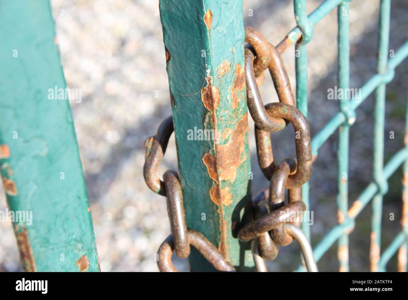 The chain with a padlock locks the rusty metal gate. Stock Photo