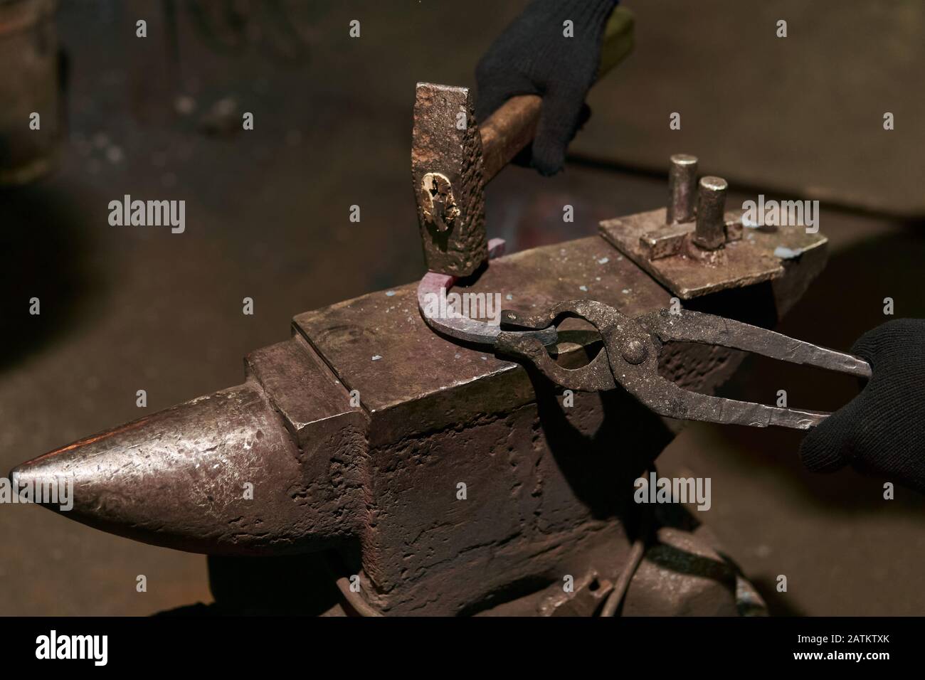 blacksmith forges a horseshoe on the anvil with bending fork, close-up