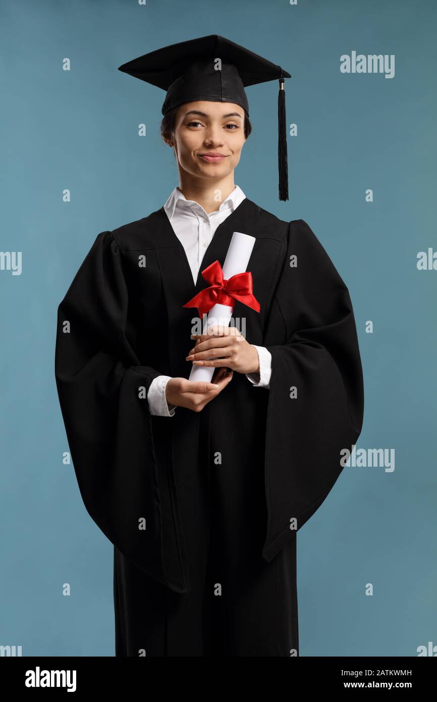 Female student in a graduation gown holding a diploma isolated on blue background Stock Photo