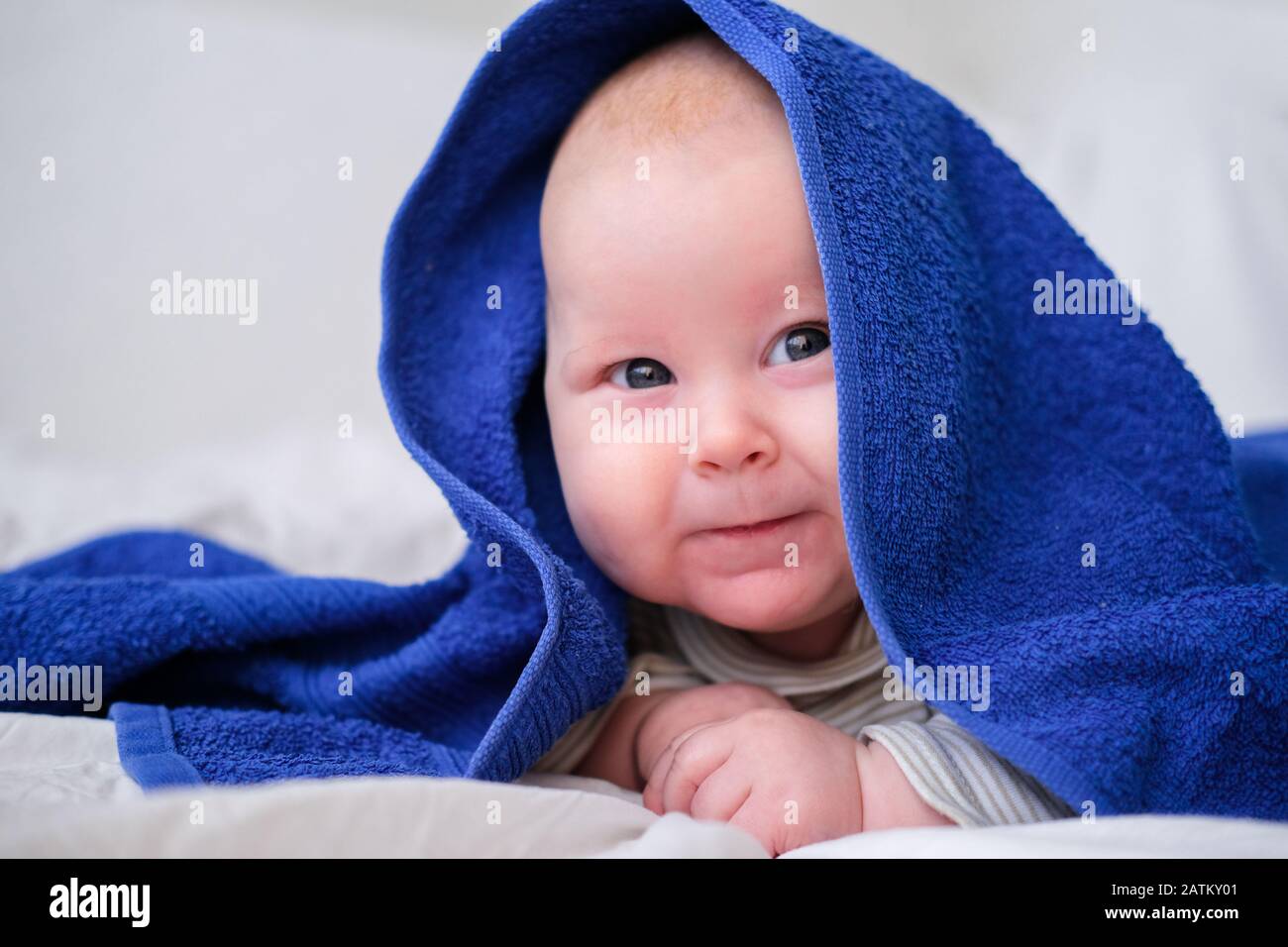 Bath time. Cute smiling caucasian infant baby looking at camera in blue
