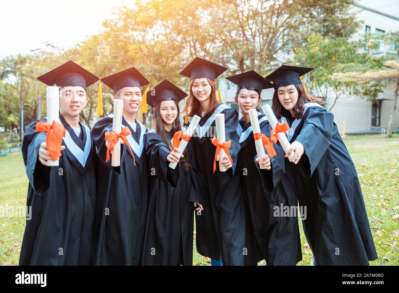 happy  students in graduation gowns holding diplomas on university campus Stock Photo