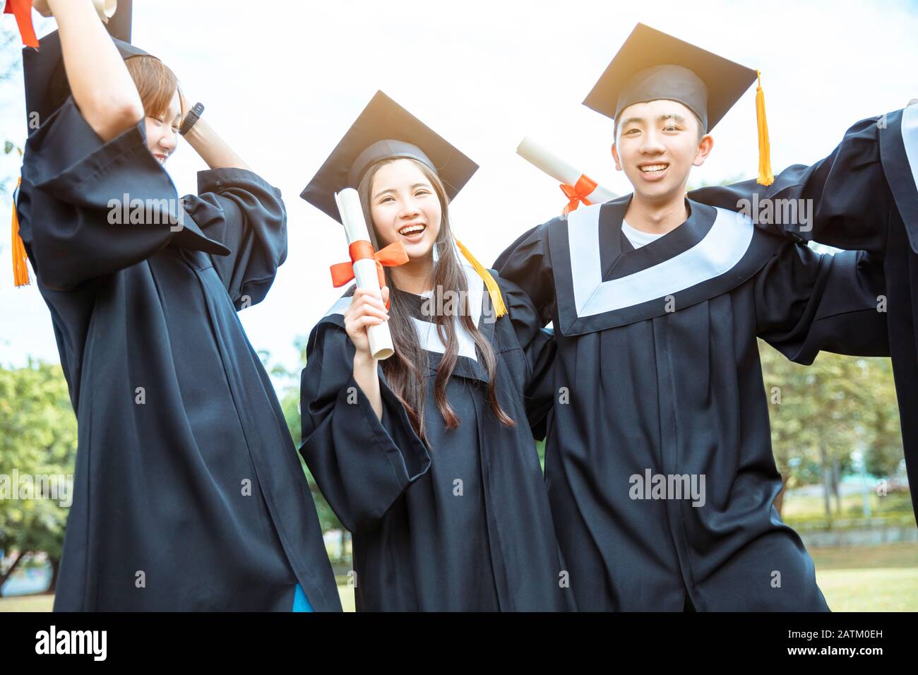 happy students in graduation gowns holding diplomas on university ...