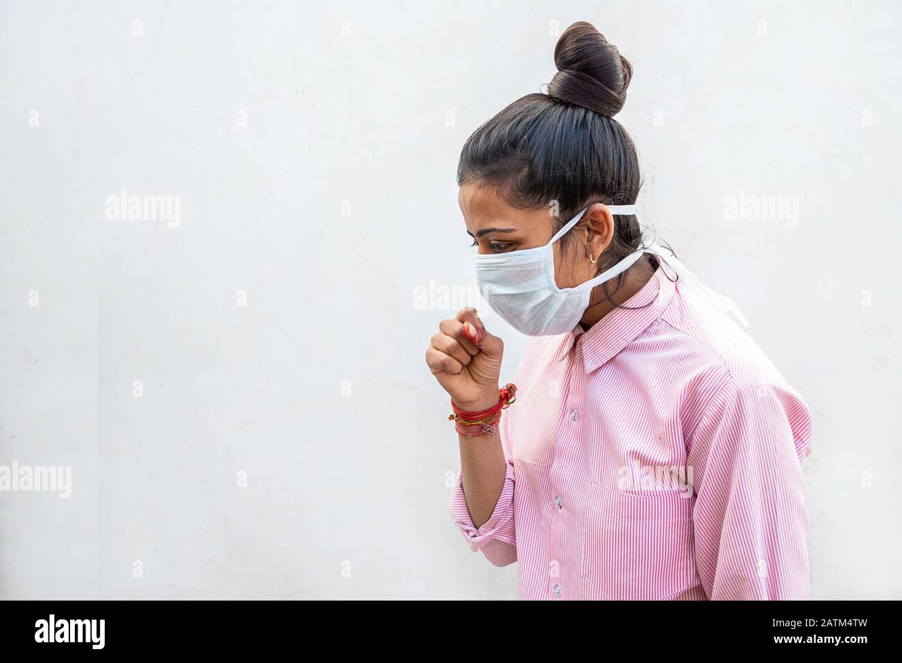Indian girl wearing breathing mask coughing as the result of spreading Coronavirus, originating in Wuhan, China. Stock Photo