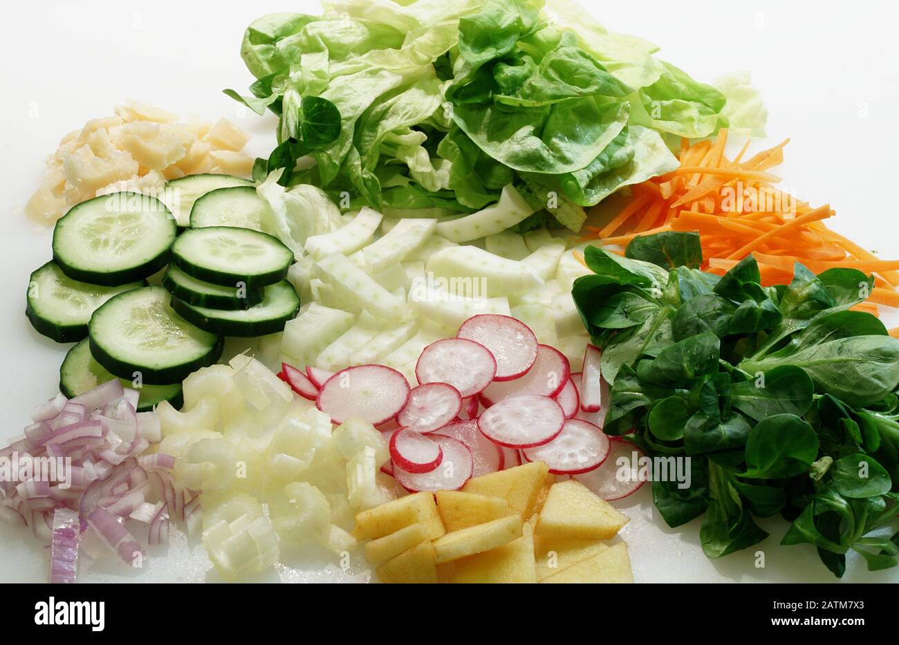 Close-up of vegetables sliced on the white cutting board for salad. Stock Photo