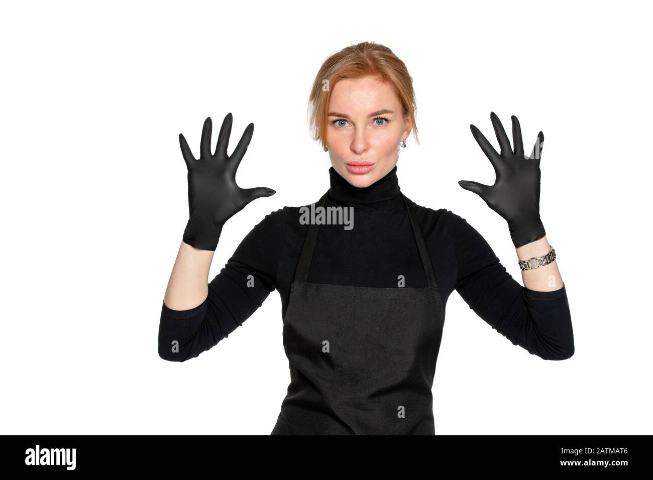 a blonde woman in black medical latex gloves poses on an isolated white background. a woman in dark clothing of a beauty salon employee. the concept of hygiene and protection Stock Photo