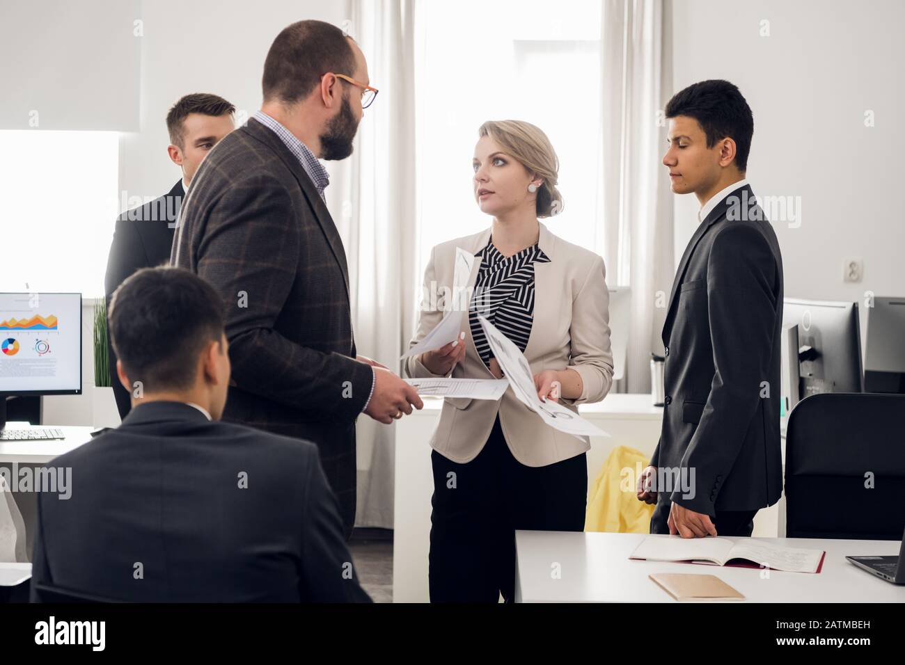 Lady in suit with documents in her hands look agressively with her chief, coworkers stand around them in the office Stock Photo