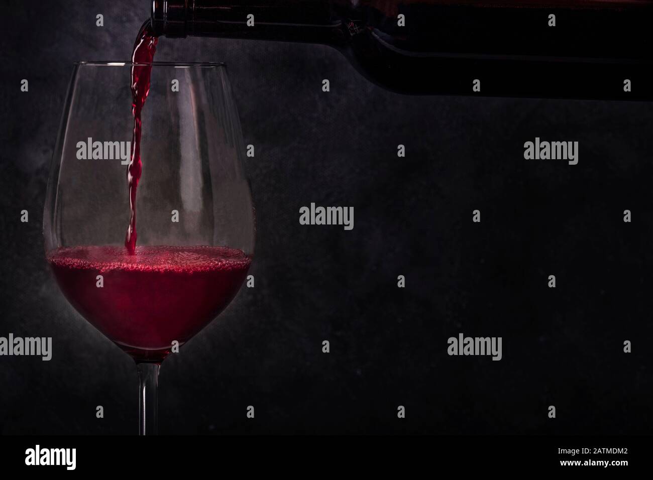Pouring wine into a glass from a bottle, side view on a black background with a place for text Stock Photo
