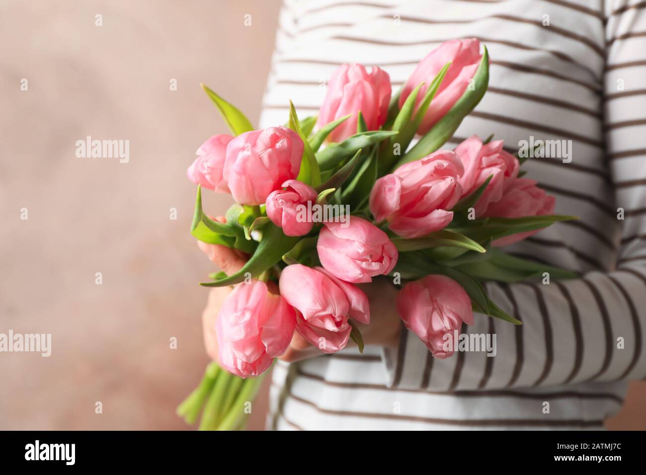 Woman holding bouquet of tulips on brown background, close up Stock Photo