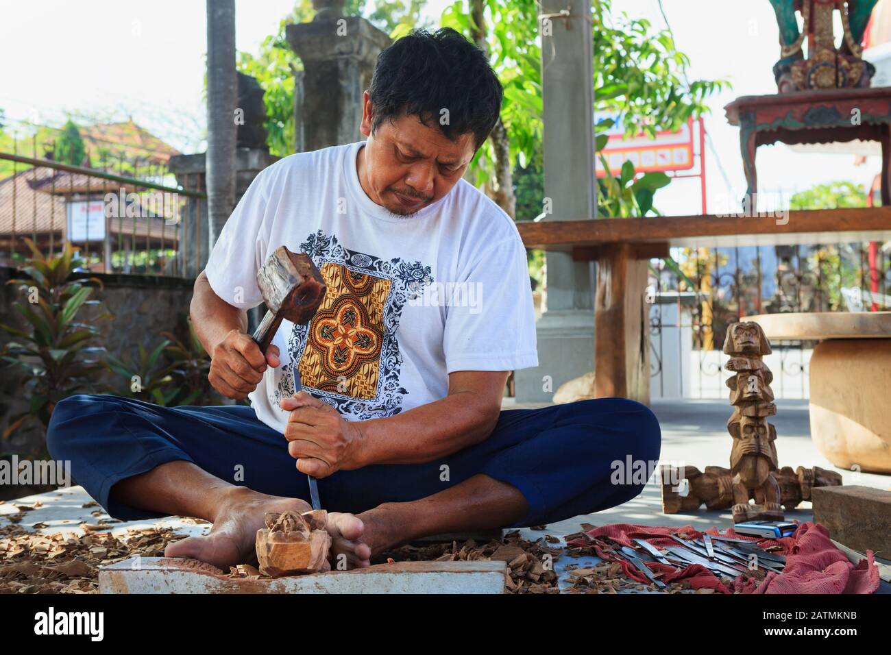 Ubud village, Bali Island, Indonesia - October 10, 2016: Balinese man working hard in wooden shop. Making traditional art souvenirs - carving by hands Stock Photo