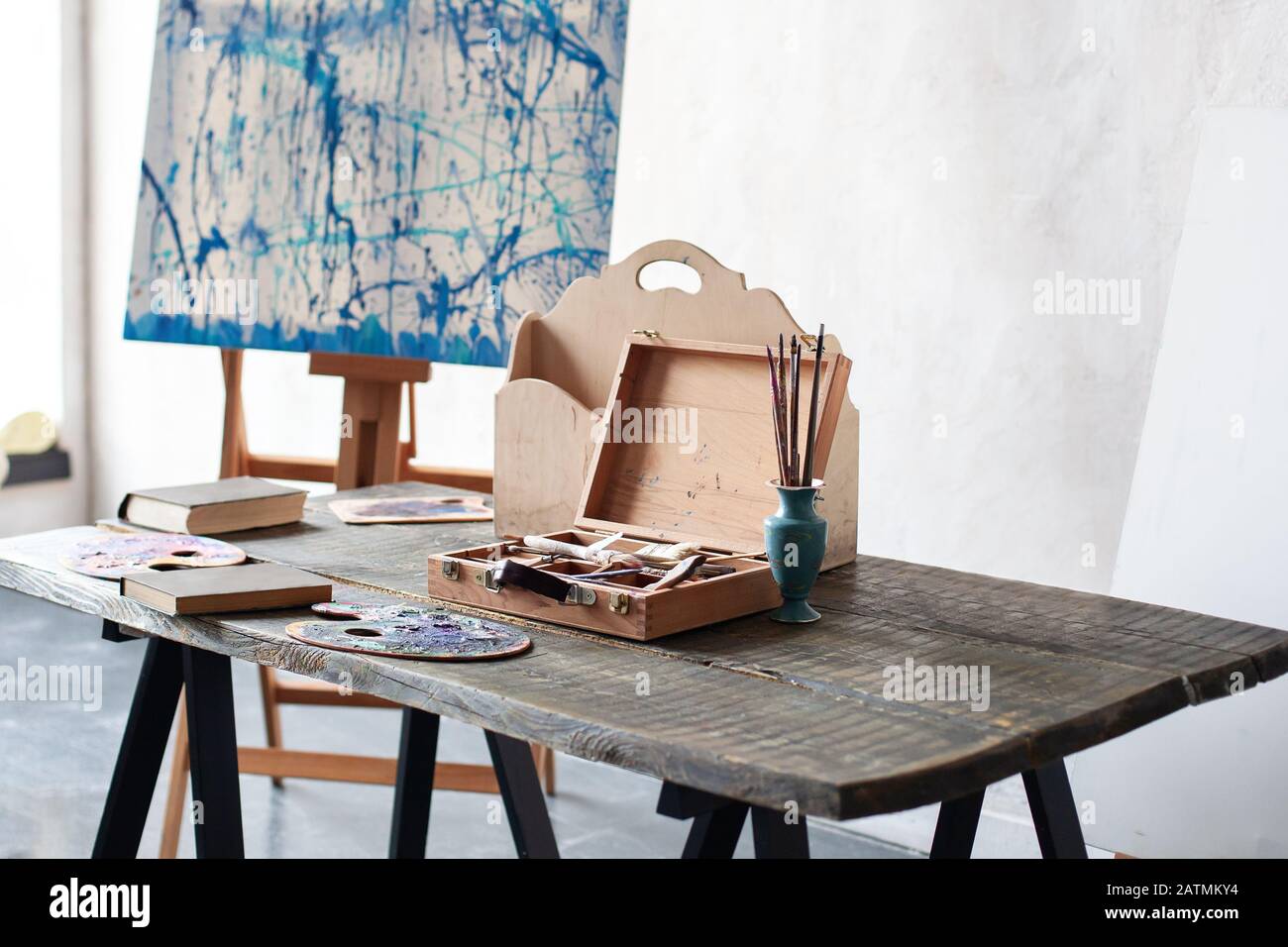 https://c8.alamy.com/comp/2ATMKY4/workplace-of-the-artist-artwork-tools-on-a-wooden-table-clutter-in-artists-workshop-watercolors-brushes-palette-easel-and-painting-tools-2ATMKY4.jpg