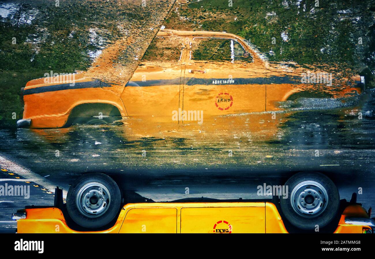 An Ambassador yellow taxi is reflected on street water in Kolkata, India. Stock Photo