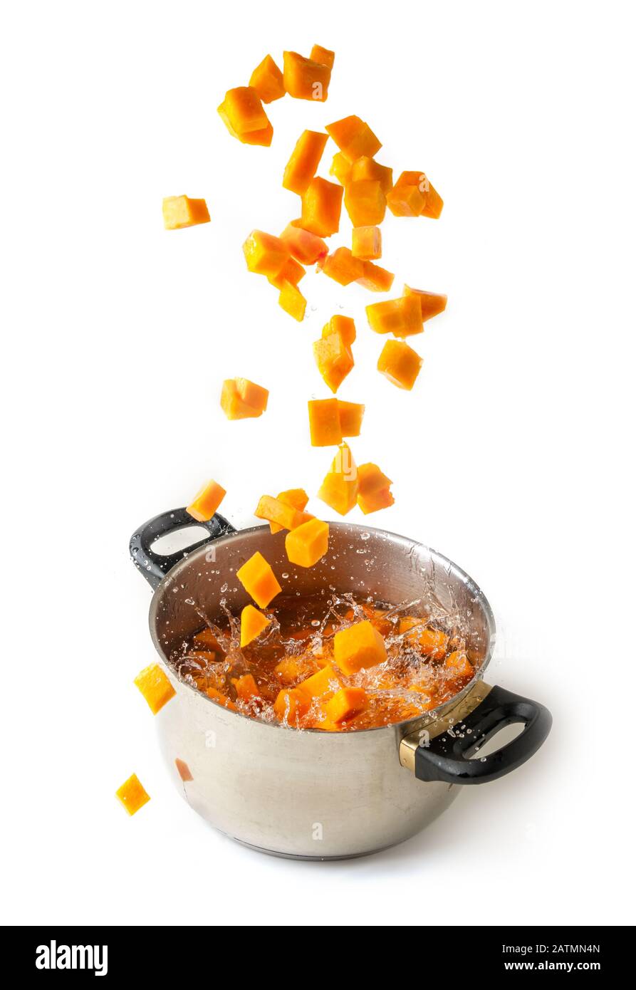 Diced pumpkin falling in a boiling pot, isolated white background Stock Photo